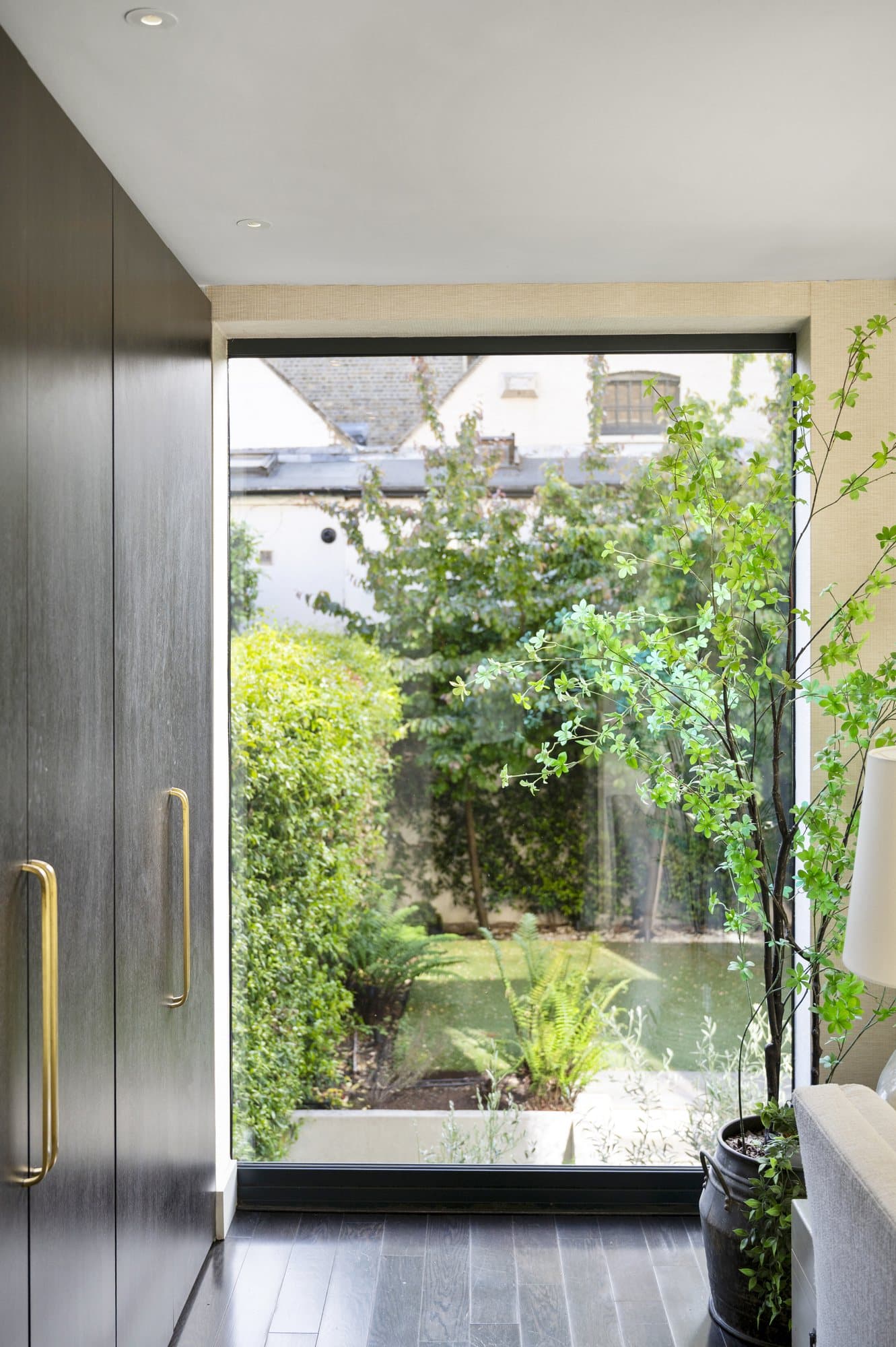 Dark kitchen cabinetry beside a full-height window onto a garden