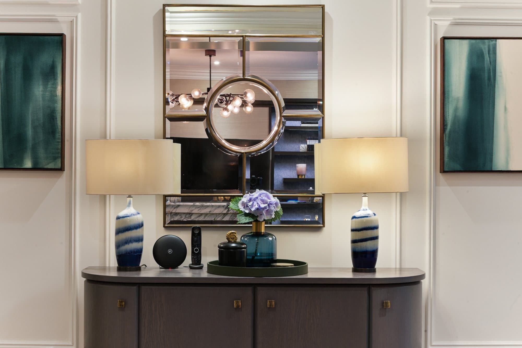 Console table with lamps and a round mirror