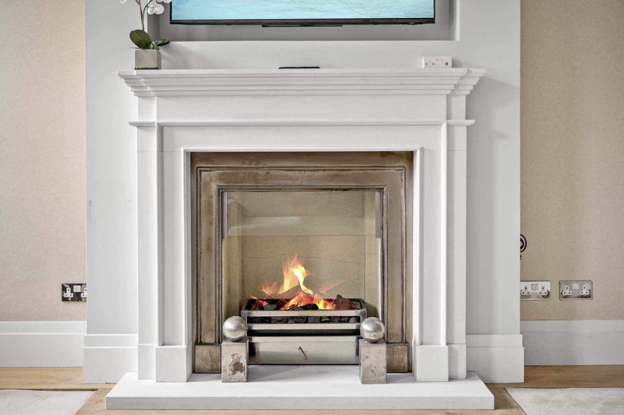 Stone fireplace with a lit fire in a South Kensington reception room