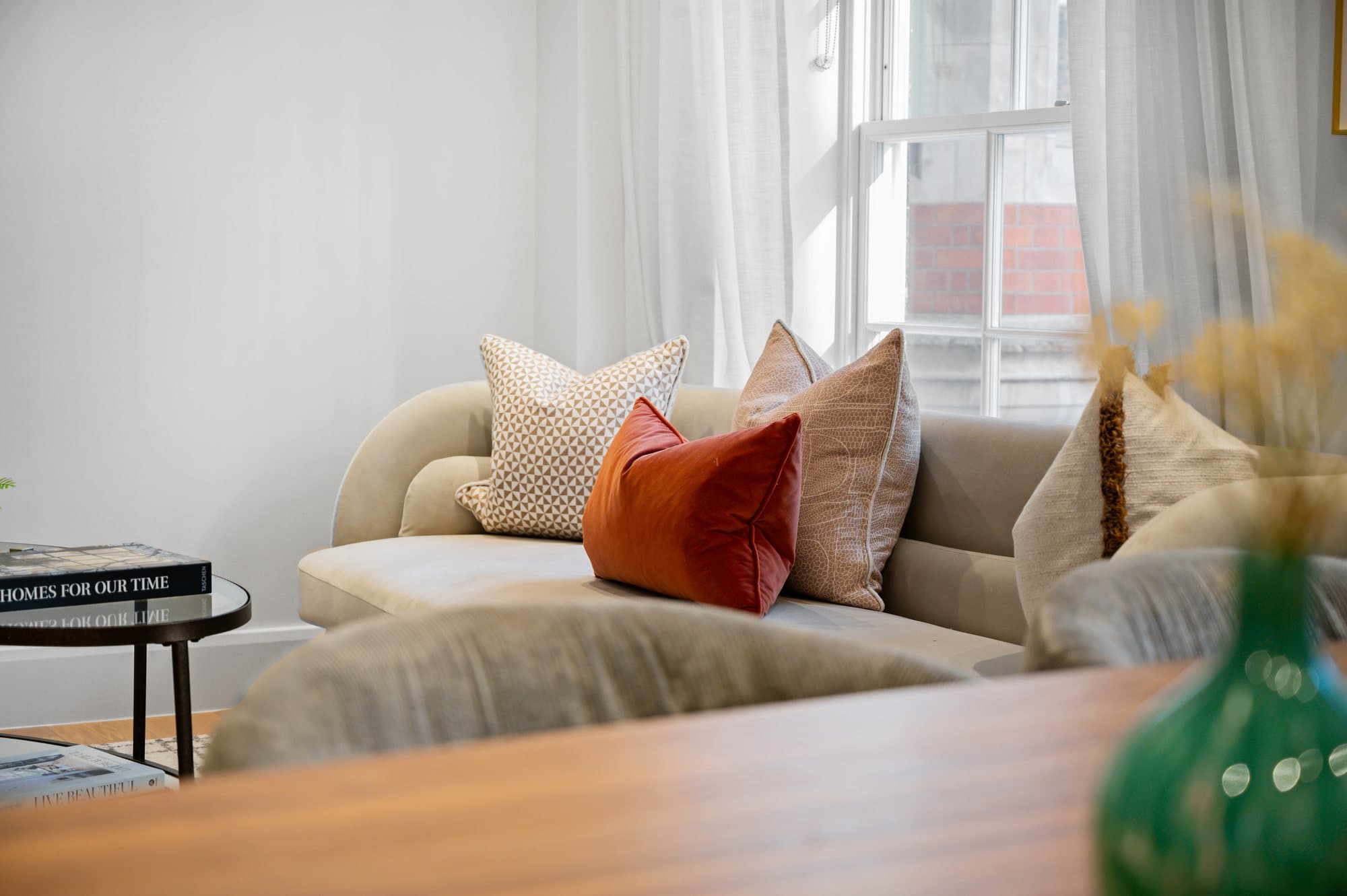Cream sofa with a patterned cushion and an orange velvet bolster at Strand