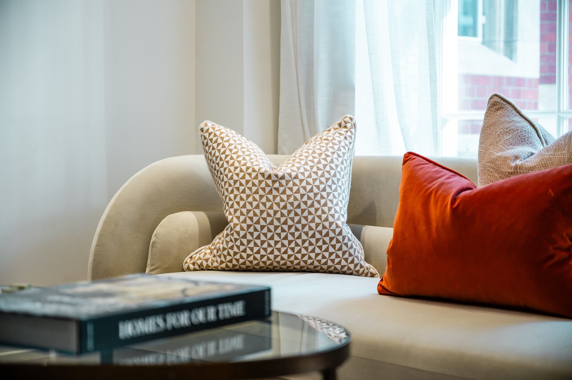 Cream sofa with a patterned cushion and an orange velvet bolster at Strand
